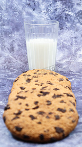 美国无麸质巧克力曲奇饼，灰色背景上有玻璃杯植物奶。