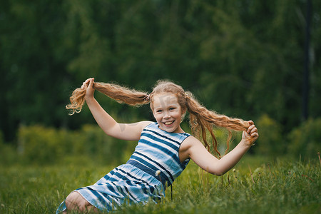 穿着蓝色夏装的微笑小女孩正在公园里玩耍