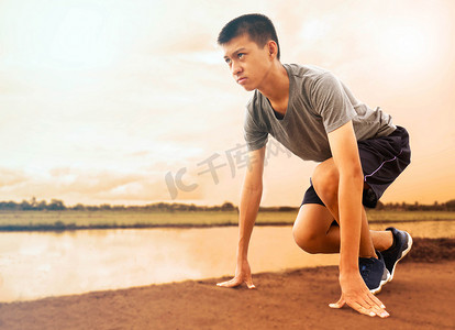 健康而自信的亚洲年轻人处于起始位置，准备跑步。