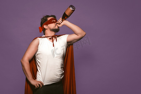 超级反英雄男人从瓶子的喉咙里喝酒。