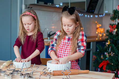 小女孩在装饰精美的客厅的壁炉旁制作圣诞姜饼屋。