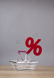 从超市的购物车有标志百分比的在灰色纸背景。