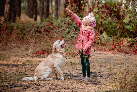 在秋天的大自然中和狗玩耍的小女孩