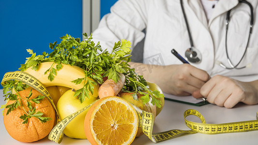 营养学家摄影照片_带卷尺的营养师办公桌的新鲜健康水果。