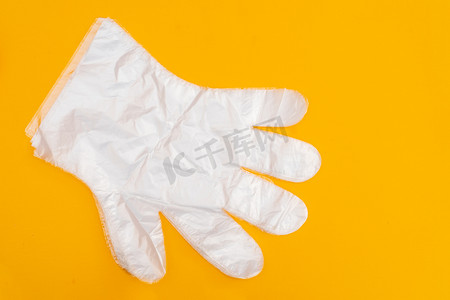 黄色背景上的透明白色防护手套。