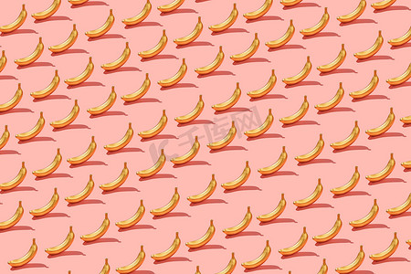 时尚阳光夏季图案黄色香蕉明亮的浅粉色背景。