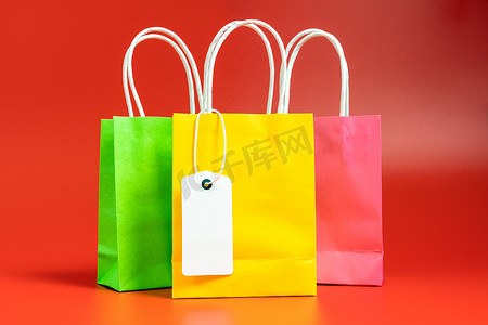 黄色、绿色和粉色的购物袋或礼品袋，用红色隔开
