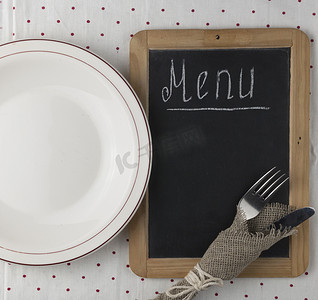 菜单标题写在黑板上的白色粉笔与桌子设置刀叉躺在桌布圆点上。