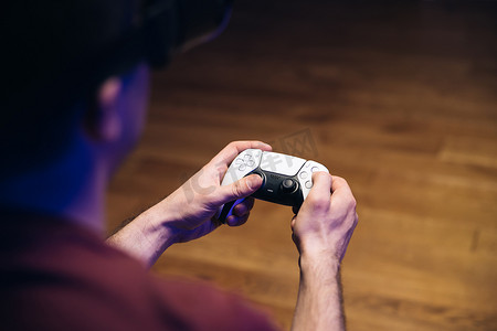 男人的手在电视宽屏前的游戏机上玩视频游戏的特写镜头。