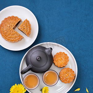 中月饼摄影照片_中秋节蓝色背景的简约布局月饼，创意食品设计理念，顶视图，平躺，复制空间。