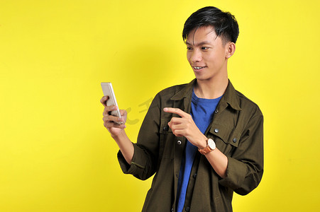 年轻帅气的亚洲男子用智能手机微笑，很高兴