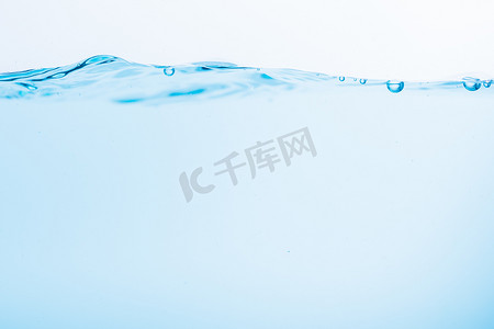 白色气泡摄影照片_蓝色水波的表面溅在白色背景上