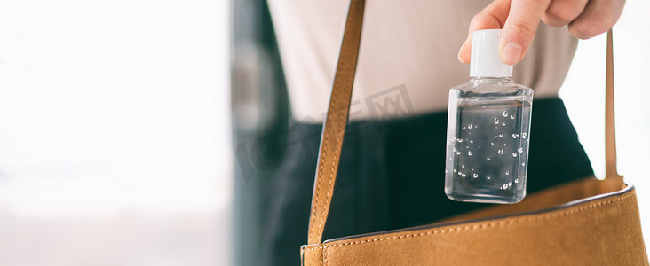 差事摄影照片_手部清洁剂旅行瓶女性携带钱包 COVID-19 预防酒精凝胶，用于在外出差事时清洁双手。