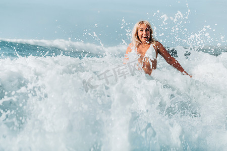 浪花水滴摄影照片_一个头发湿漉漉的女孩跳过大西洋的大浪，绕着浪花和水滴飞溅。特内里费岛。西班牙