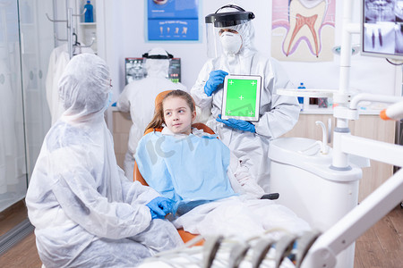 牙医在 ppe 套装中使用的带绿屏的平板电脑