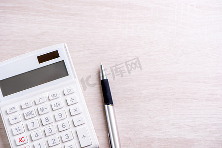 明亮木桌上的白色计算器和笔、财务利润分析和统计、投资风险概念、复制空间、顶视图平躺