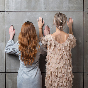 个护摄影照片_两个女孩靠墙站着，后视图。