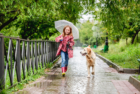 雨中街道摄影照片_带着狗在雨中行走的小女孩
