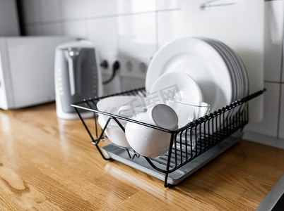 碗碟架可在木制台面、白色墙砖、水槽和水龙头上放置许多碗碟和杯子。