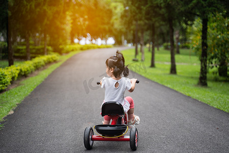 宝宝穿棉衣服摄影照片_可爱的宝宝在花园里骑自行车