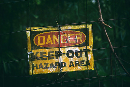 危险标志，上面写着“请勿进入危险区域”，作为警告信息，悬挂在围栏暗区上，外面有脏海报
