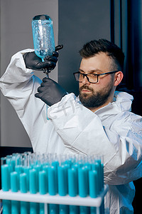 一位身穿防护服的男科学家装有蓝色疫苗液