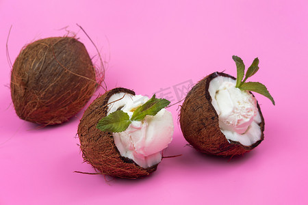 粉红色背景中用薄荷叶装饰的新鲜椰子半香草冰淇淋球