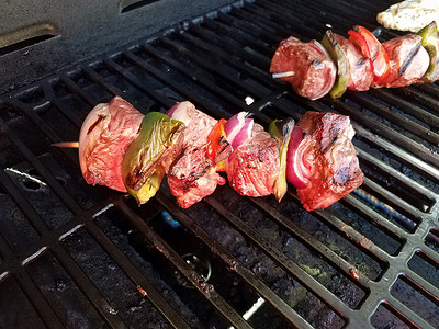 牛肉烤肉串配洋葱和辣椒，放在烤架上，配鸡肉