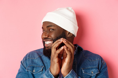 狡猾的非洲裔美国男性模特的特写镜头有一个想法，策划一些事情，尖顶的手指和狡猾的微笑，站在粉红色的背景上