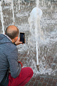 水流图片摄影照片_游客拍摄喷泉的水流