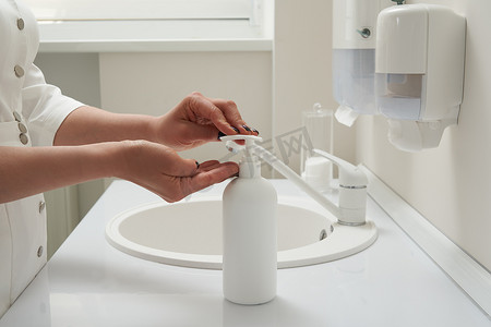 上洗手摄影照片_在水槽洗手前女性手按在肥皂瓶上的剪影