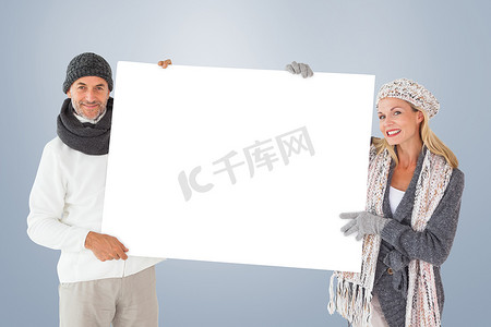 冬季时尚中微笑情侣拿着海报的复合图像
