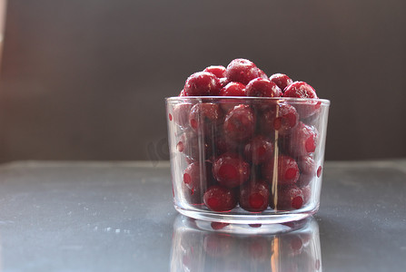 玻璃餐具摄影照片_食物照片冷冻樱桃或黑色背景玻璃餐具中的樱桃，并有文字可以吃复制空间