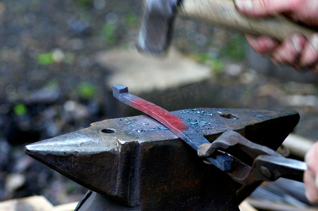 铁匠在锻造厂的铁砧上用锤子加工金属
