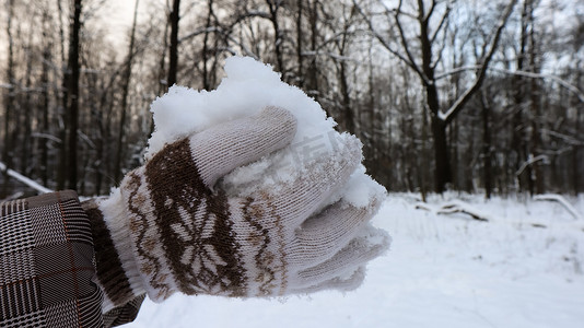 冬天，戴着针织手套的女人的手在外面握着天然柔软的白雪。