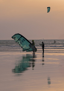 风筝摄影照片_太阳落山时，风筝冲浪者从海上归来