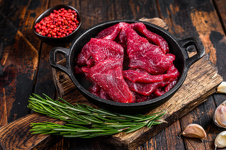 铸铁锅中新鲜生切的红牛肉菲力片。