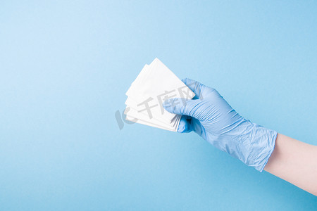 蓝色一次性医用手套的手拿着一次性纸巾、鼻子卫生、流鼻涕和感冒概念