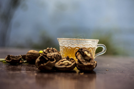 壁摄影照片_透明玻璃杯中壁坚果或核桃茶的草药有机茶的特写，壳内有生壁坚果，也破碎。