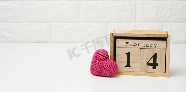 日期为 2 月 14 日的木历和红色针织心、白桌