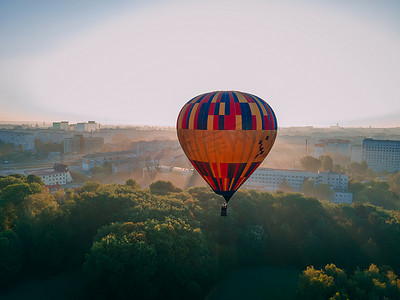 彩色气球热气球摄影照片_夏季日出时，彩色热气球从欧洲小城市的绿色公园起飞