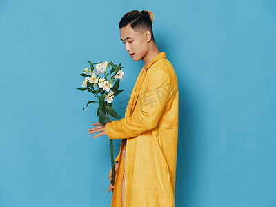 一个身穿黄色外套、蓝色背景上有一束鲜花的男人的侧视图