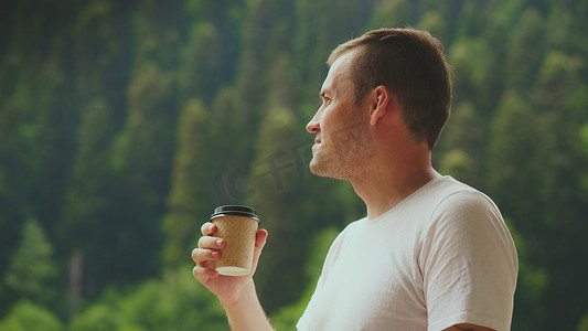 愉快的人花时间享受假期和在山林背景下喝咖啡的肖像。