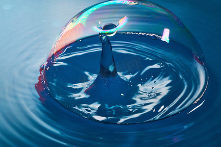 水流碰撞摄影照片_水滴几乎破裂成气泡与另一股水流碰撞时的蓝色表面和气泡