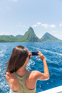 手机夏季夏季摄影照片_加勒比海旅行女孩在圣卢西亚皮通斯游船上用手机拍照，享受热带度假的夏季生活方式。