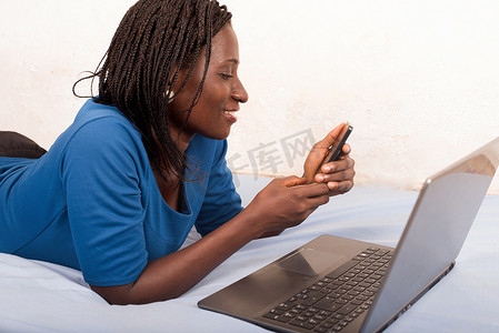 年轻微笑的女人在床上用手机聊天