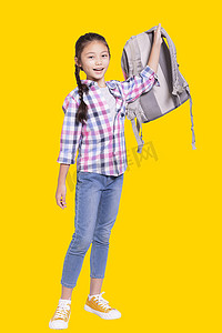 一个快乐的女学生带着包的全长画像。在黄色背景上被隔离。