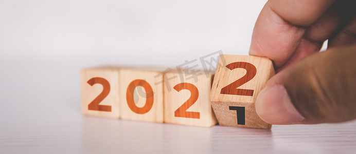 双手翻转立方体木块，文字为 2022 年、开始和趋势、日历和时间、确定目标和成就规划、动机和愿望、商业概念。