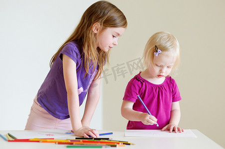 孩子彩色铅笔摄影照片_两个小姐妹用彩色铅笔画画