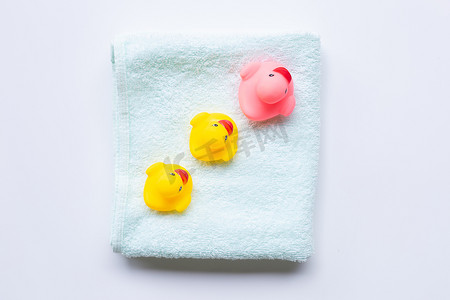 柔软的绿色毛巾上的粉色和黄色鸭子玩具，白色背景